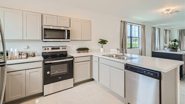 kitchen featuring a sink, a peninsula, stainless steel appliances, light countertops, and light tile patterned floors