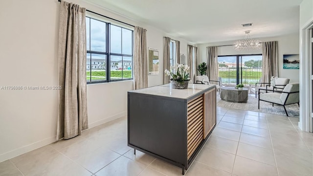 kitchen featuring a kitchen island, a wealth of natural light, a notable chandelier, and baseboards