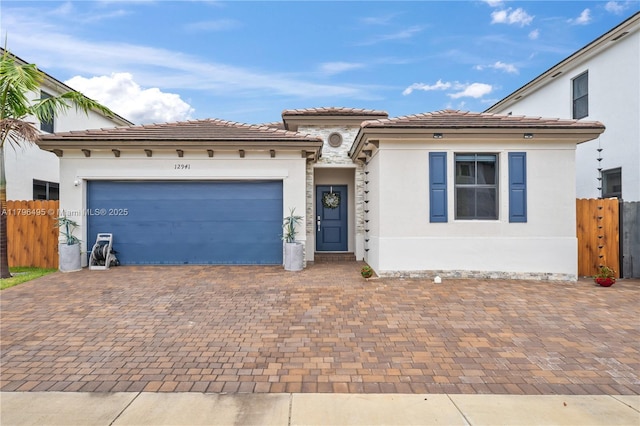view of front of property featuring driveway, fence, an attached garage, stucco siding, and a tile roof