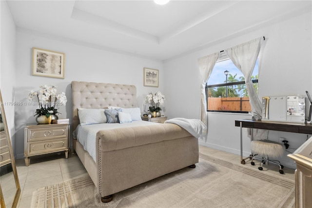 bedroom featuring light tile patterned floors, a raised ceiling, and baseboards