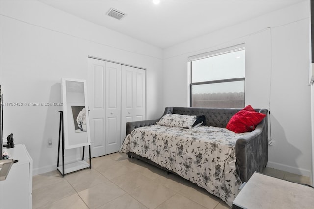 bedroom featuring baseboards, light tile patterned floors, visible vents, and a closet
