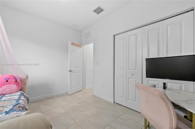 bedroom with baseboards, light tile patterned floors, visible vents, and a closet