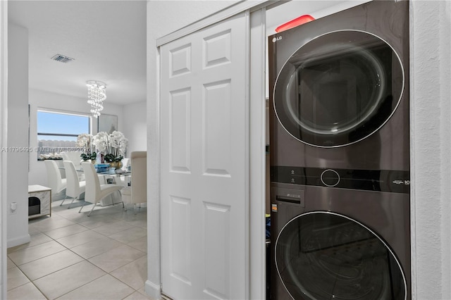 laundry area featuring stacked washer and clothes dryer, light tile patterned floors, laundry area, a notable chandelier, and visible vents