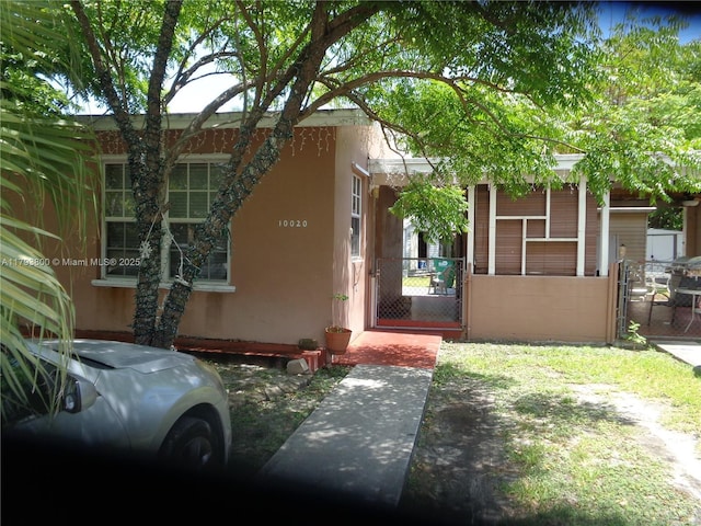 doorway to property featuring stucco siding and a gate