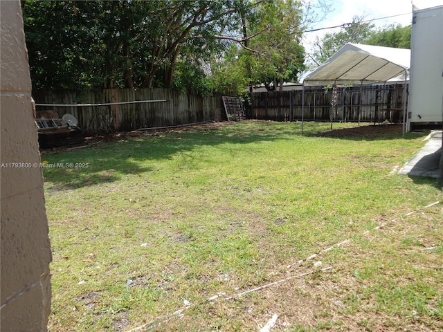 view of yard with a fenced backyard and a carport