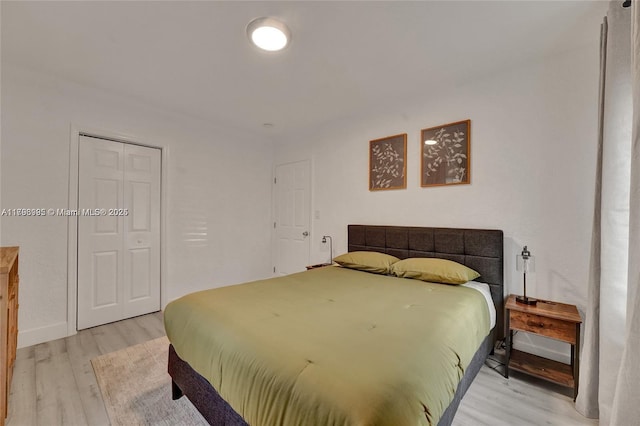 bedroom with a closet, light wood-type flooring, and baseboards