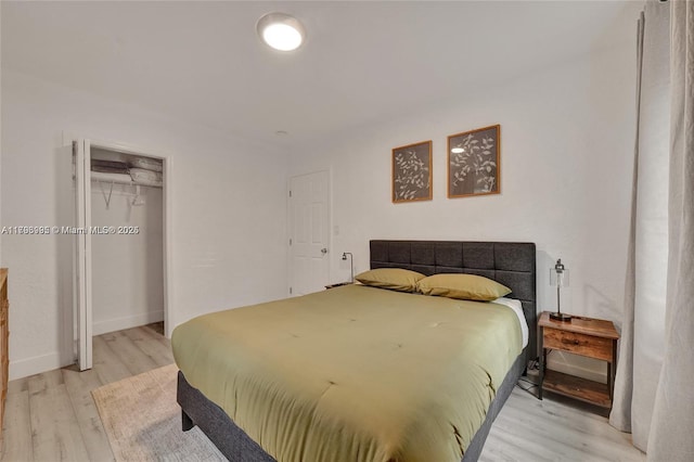 bedroom featuring baseboards, light wood finished floors, and a closet