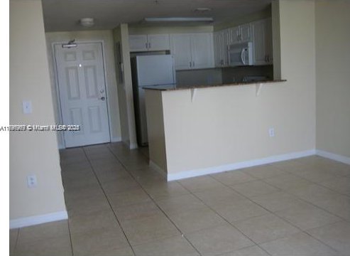 215 SW 42nd Ave Unit 905, Miami, FL 33134 - kitchen featuring stainless steel microwave, a peninsula, freestanding refrigerator, dark countertops, and light tile patterned floors