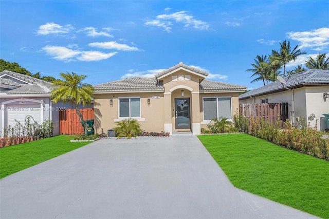 view of front of property featuring a front lawn, a tiled roof, stucco siding, and fence