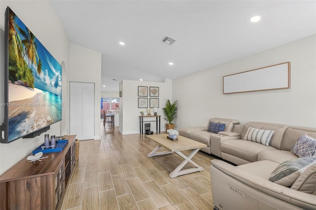 living area featuring vaulted ceiling, light wood-style floors, visible vents, and recessed lighting