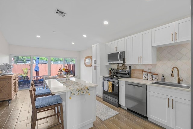 kitchen featuring a sink, white cabinets, light countertops, appliances with stainless steel finishes, and tasteful backsplash