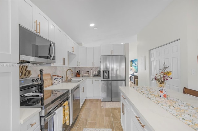 kitchen with recessed lighting, a sink, decorative backsplash, light countertops, and appliances with stainless steel finishes