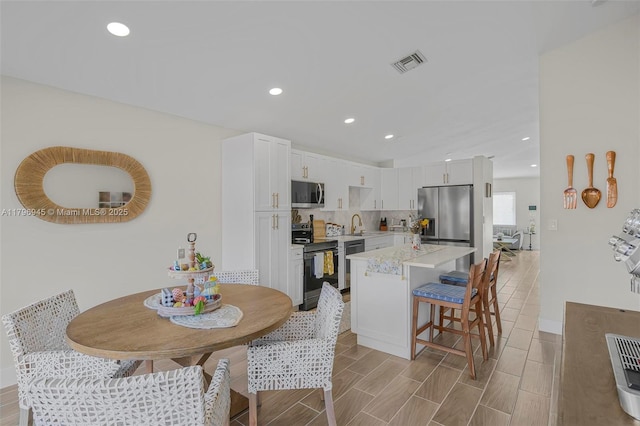 kitchen featuring a breakfast bar area, visible vents, white cabinets, a kitchen island, and appliances with stainless steel finishes