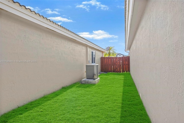 view of yard featuring central AC unit and fence