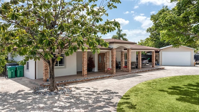 view of front facade featuring covered porch, stucco siding, a front lawn, an outbuilding, and driveway