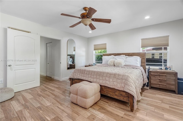 bedroom featuring light wood finished floors, arched walkways, a ceiling fan, and recessed lighting