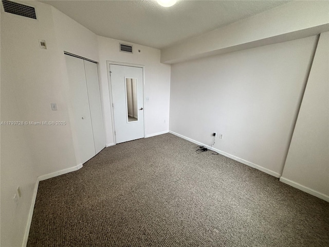 empty room with visible vents, baseboards, and dark colored carpet