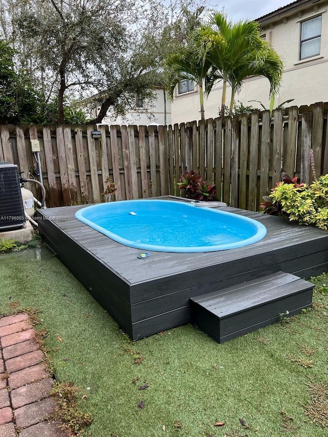 view of swimming pool with central air condition unit, fence, and a jacuzzi