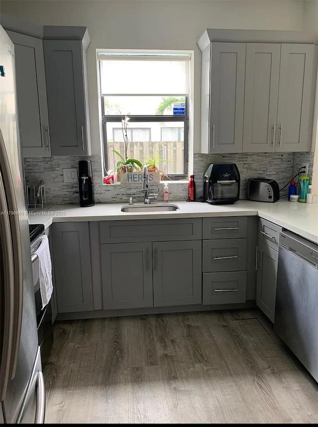 kitchen featuring a sink, stainless steel appliances, gray cabinetry, and tasteful backsplash
