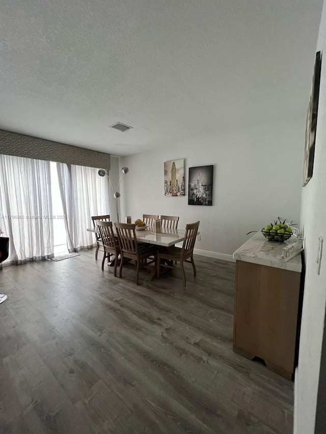 dining room featuring a textured ceiling, baseboards, dark wood-style floors, and visible vents