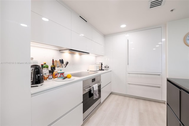 kitchen featuring light wood finished floors, modern cabinets, visible vents, white cabinets, and oven