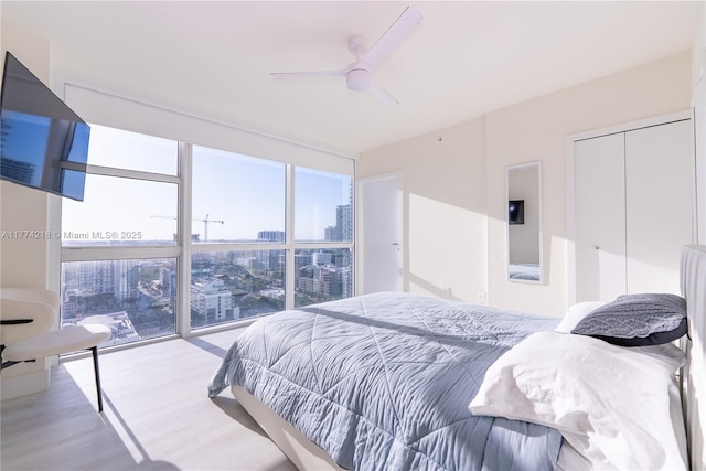 bedroom featuring a city view, wood finished floors, and a ceiling fan