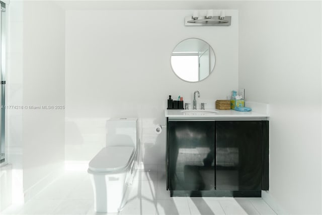 bathroom with vanity, toilet, baseboards, and tile patterned flooring