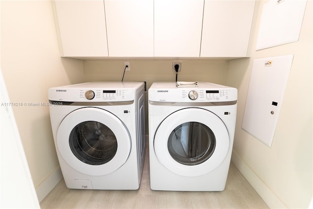 clothes washing area with washing machine and clothes dryer, cabinet space, and baseboards