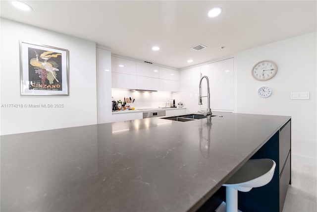 kitchen featuring recessed lighting, modern cabinets, visible vents, a sink, and white cabinetry