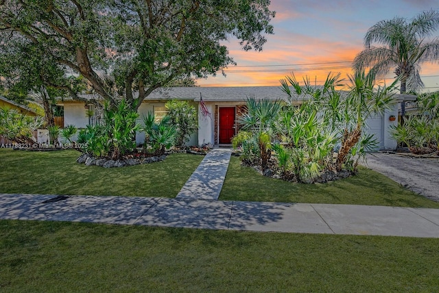 view of front facade featuring stucco siding, a front lawn, and an attached garage