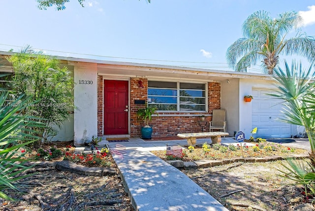property entrance featuring brick siding, stucco siding, and a garage