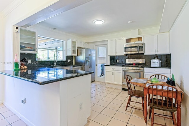 kitchen featuring a peninsula, light tile patterned floors, glass insert cabinets, white cabinets, and appliances with stainless steel finishes