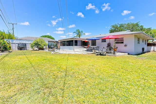 rear view of house with a sunroom, stucco siding, fence, a lawn, and a patio area