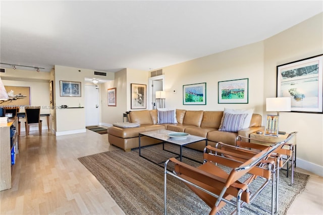 living room featuring light wood-style floors, visible vents, and baseboards