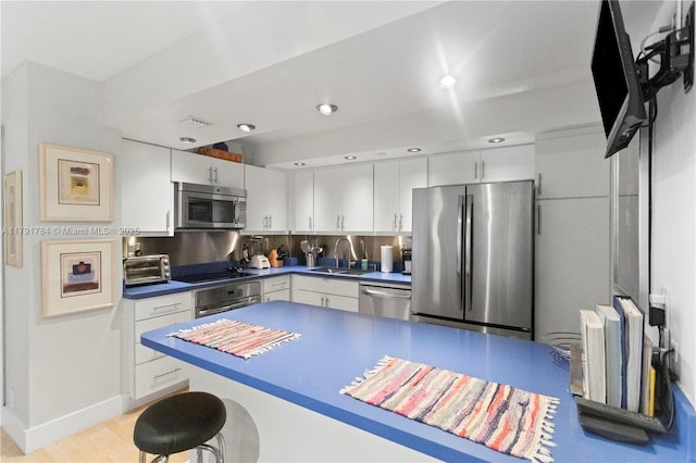 kitchen featuring white cabinetry, a breakfast bar, stainless steel appliances, and a sink