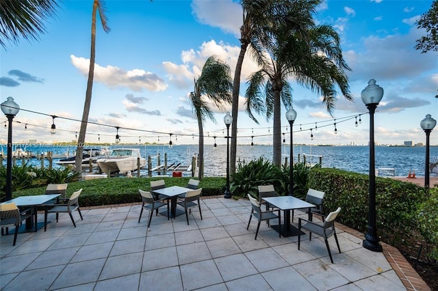 view of patio / terrace with a water view, a boat dock, and outdoor dining space