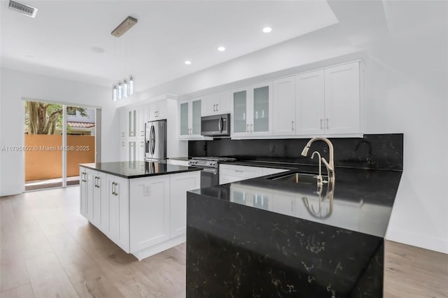 3040 NW 126th Ave, Sunrise, FL 33323 - kitchen featuring appliances with stainless steel finishes, a sink, dark countertops, a center island, and light wood finished floors
