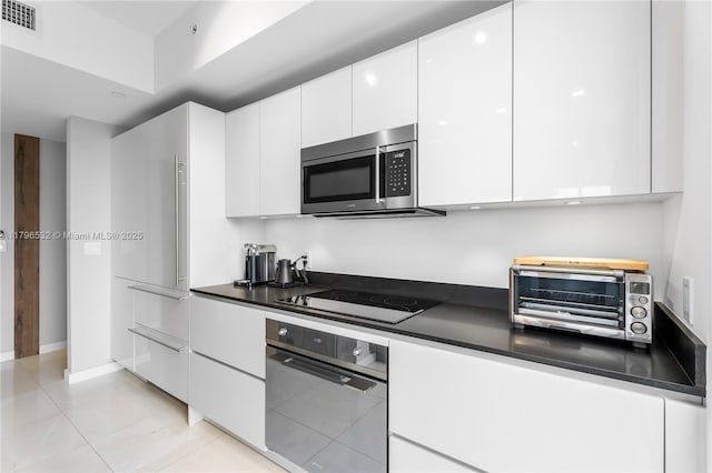 kitchen with dark countertops, a toaster, white cabinetry, visible vents, and appliances with stainless steel finishes