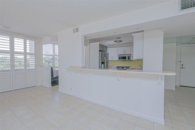 1865 Brickell Ave Unit A514, Miami, FL 33129 - kitchen with appliances with stainless steel finishes, light countertops, light tile patterned floors, a peninsula, and a kitchen breakfast bar