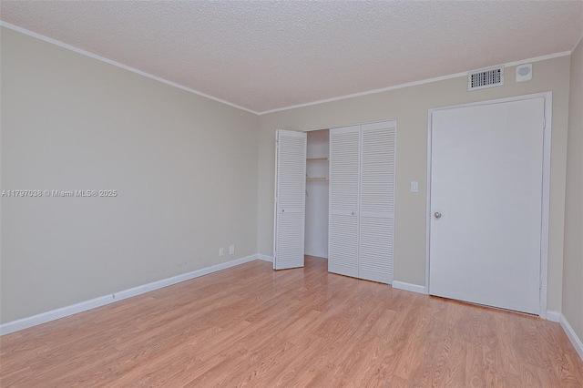 1865 Brickell Ave Unit A514, Miami, FL 33129 - unfurnished bedroom featuring light wood-style flooring, crown molding, a closet, a textured ceiling, and baseboards