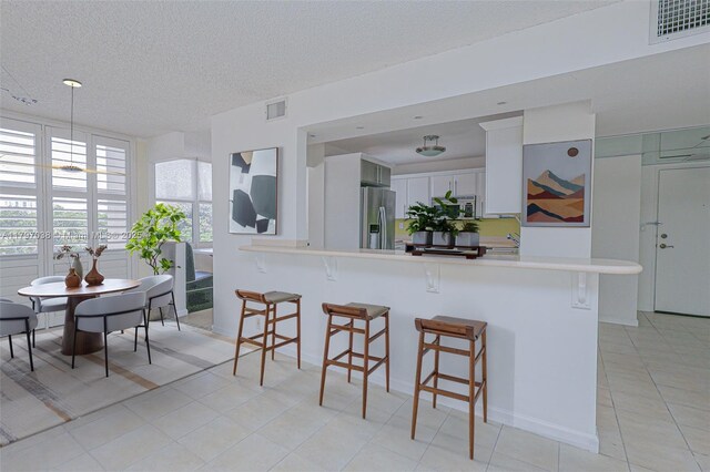 1865 Brickell Ave Unit A514, Miami, FL 33129 - kitchen featuring appliances with stainless steel finishes, a kitchen breakfast bar, light countertops, a peninsula, and a textured ceiling