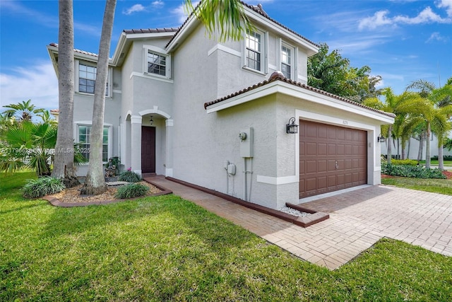 mediterranean / spanish home featuring a tile roof, a garage, stucco siding, a front yard, and decorative driveway