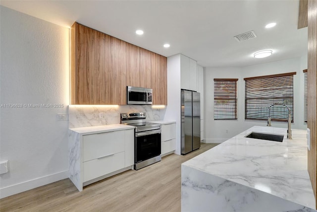 16276 SW 29th St, Miramar, FL 33027 - kitchen with stainless steel appliances, modern cabinets, a sink, decorative backsplash, and light wood finished floors