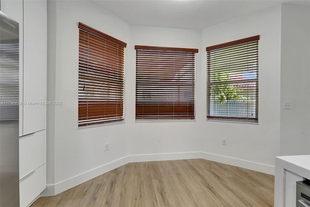 empty room with baseboards, a heating unit, and light wood-type flooring
