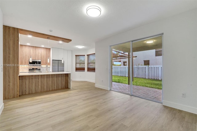 unfurnished living room featuring baseboards and light wood finished floors