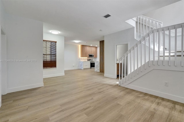 unfurnished living room featuring stairway, baseboards, light wood-style flooring, and visible vents