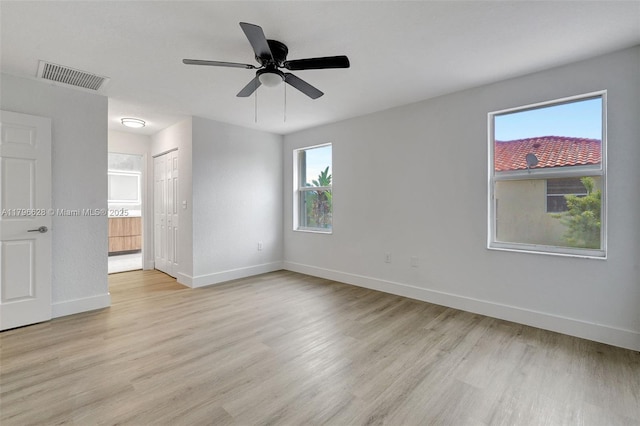 unfurnished bedroom featuring baseboards, light wood-style floors, connected bathroom, and visible vents