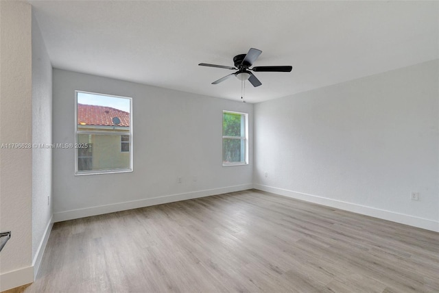 spare room featuring baseboards, light wood-style floors, and a ceiling fan