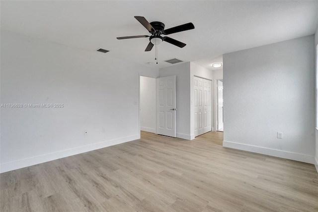spare room featuring baseboards, ceiling fan, light wood-style floors, and visible vents