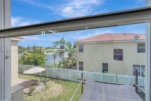 view of side of home with a water view, stucco siding, a tile roof, and a fenced backyard